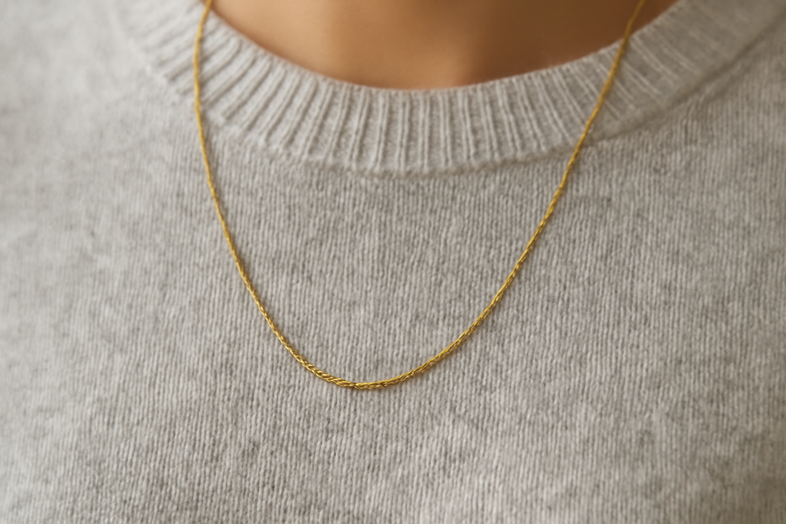 collier discret posé sur un pull monochrome