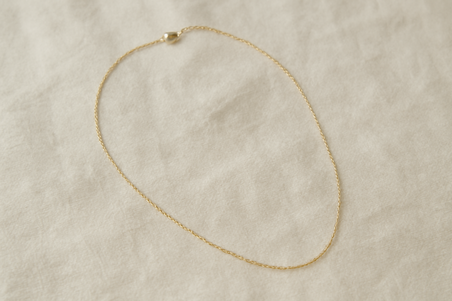 collier fin posé sur un tissu clair