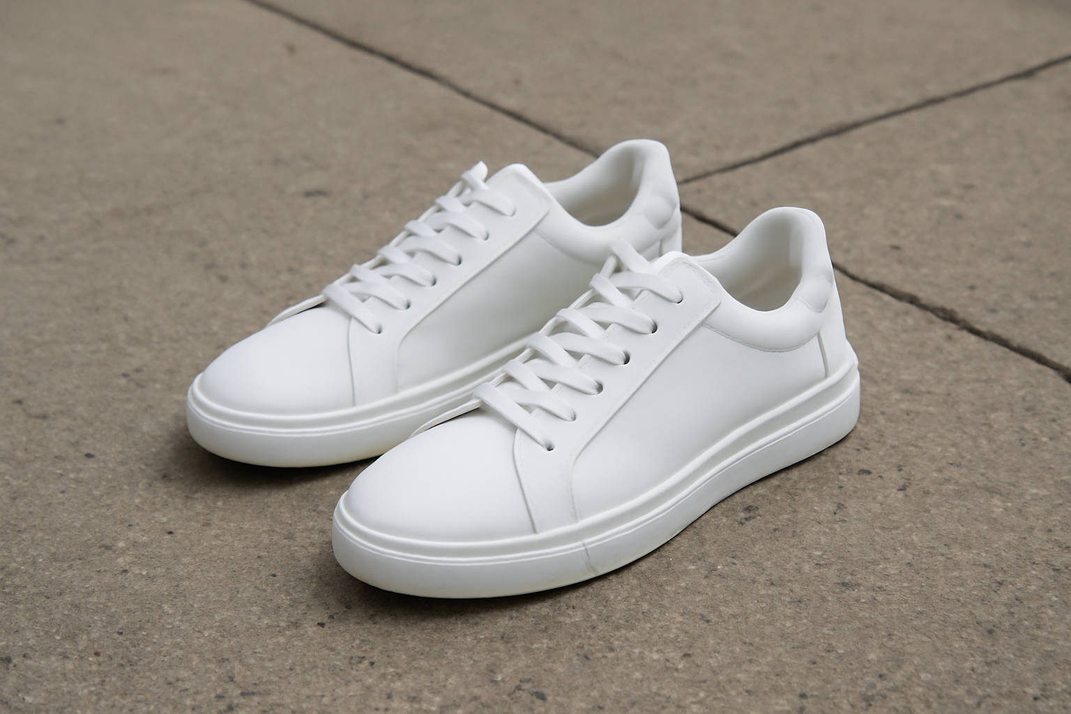 sneakers blanches sur trottoir en béton
