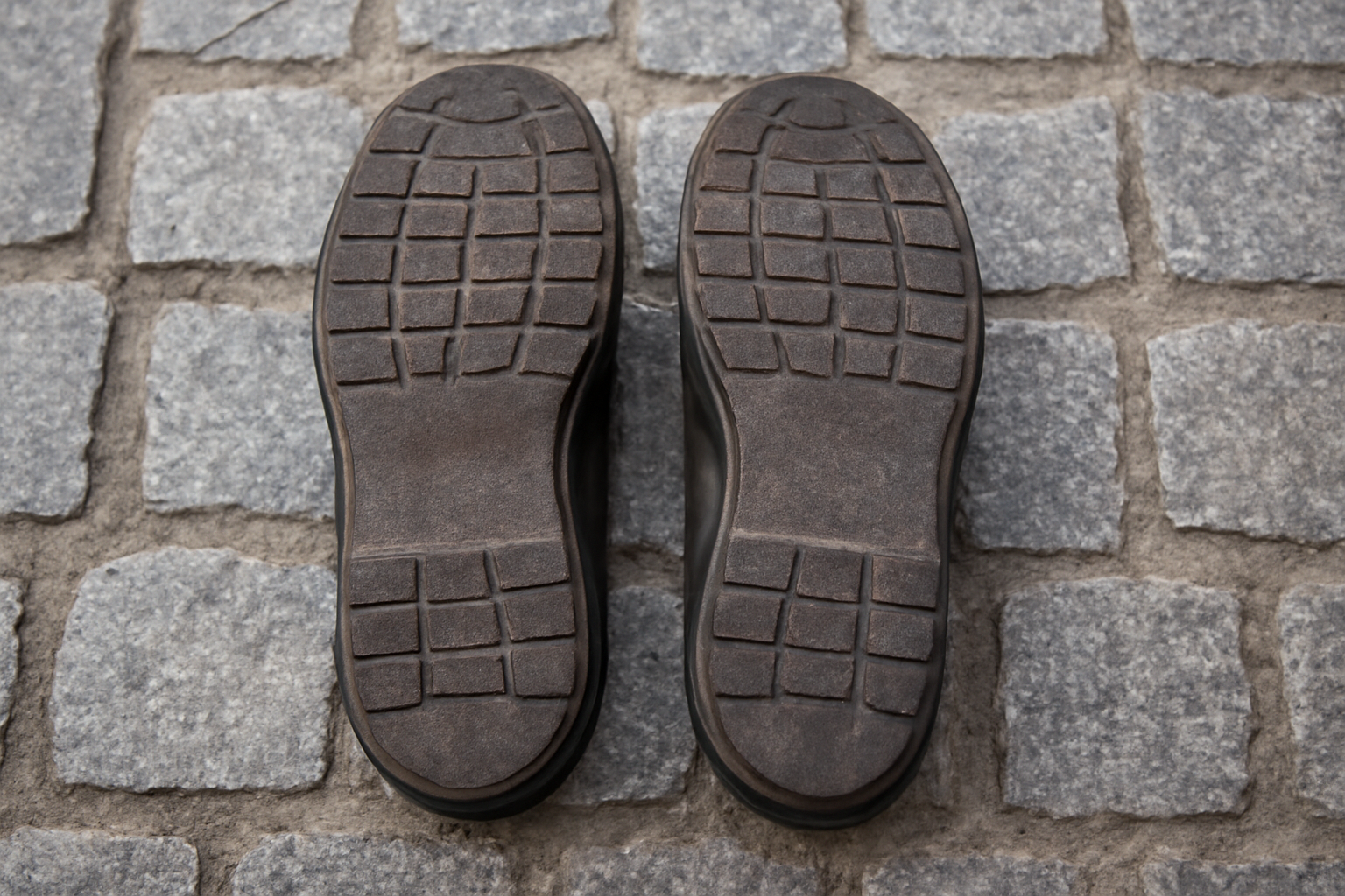 semelles de chaussures posées sur sol pavé urbain