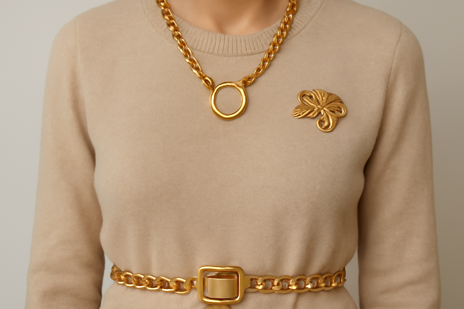 collier ceinture et broche sur pull monochrome